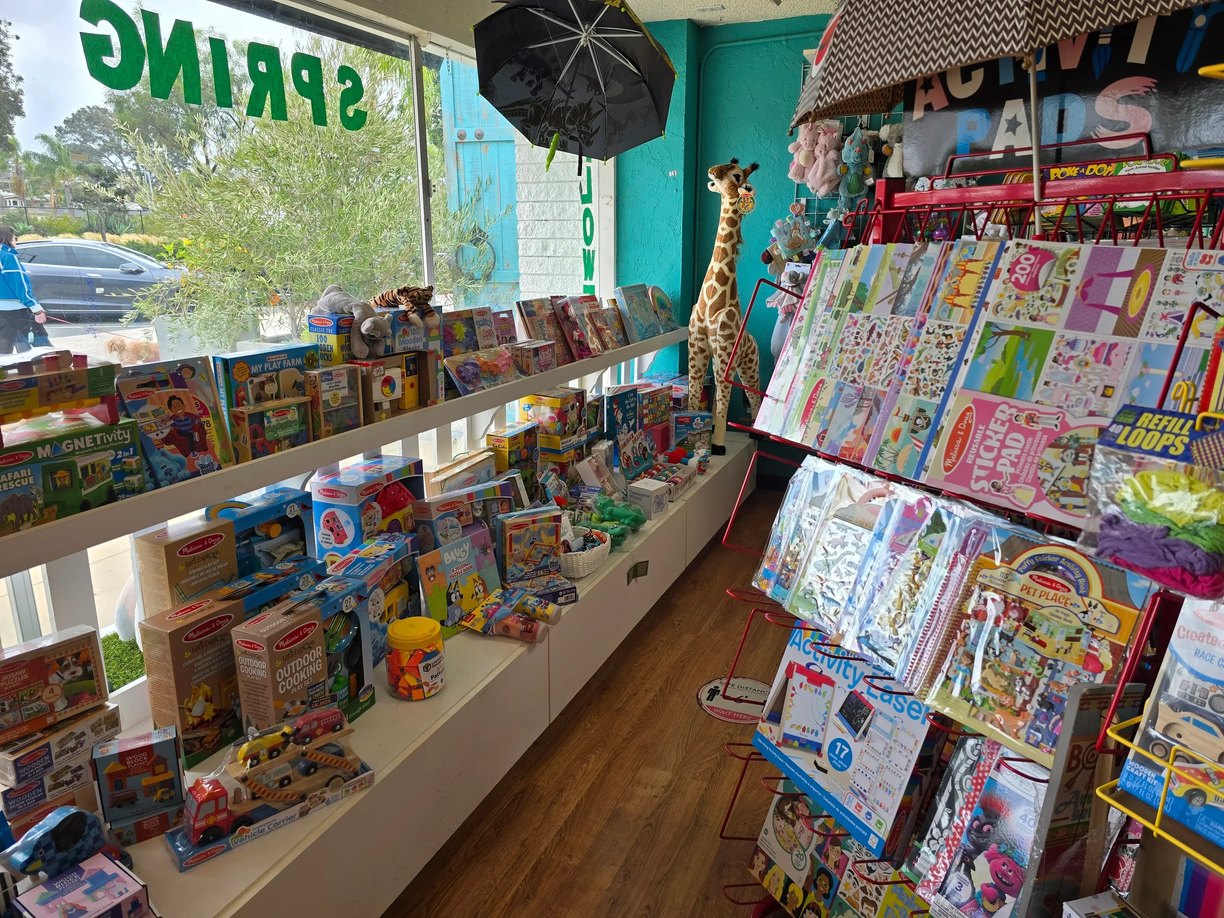 Toy store interior with shelves stocked with toys and books, and a display of children's magazines.